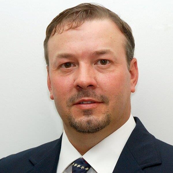 A man in suit and tie standing next to wall.